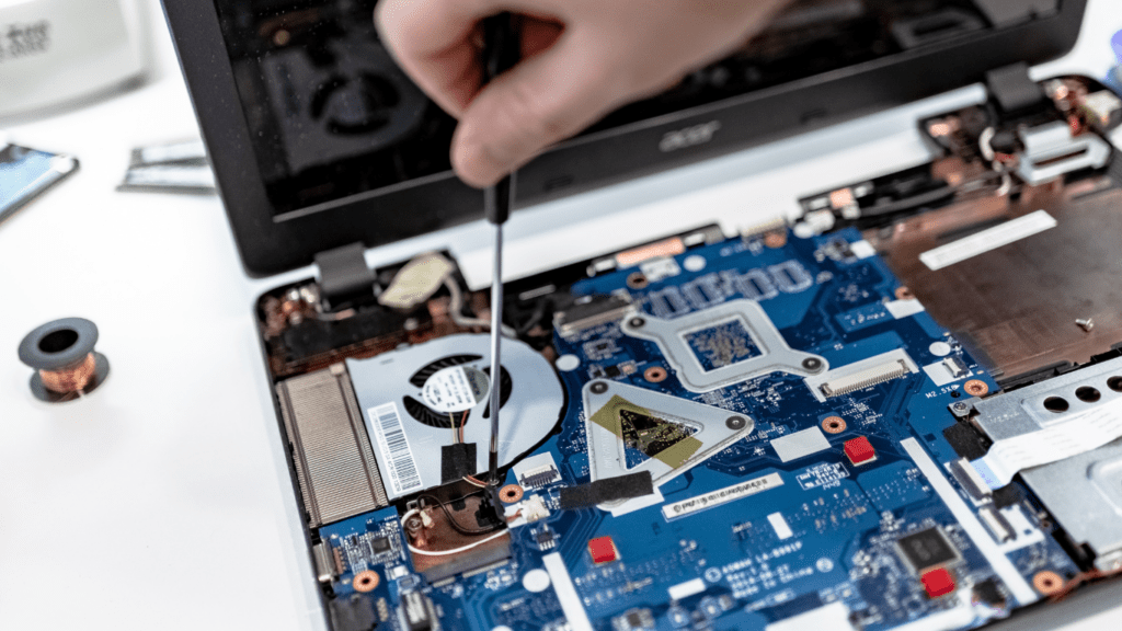 a person is repairing a laptop with a screwdriver