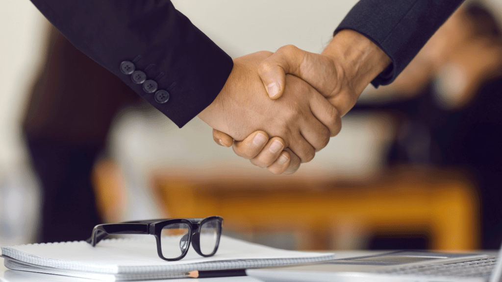 two business people shaking hands over a laptop