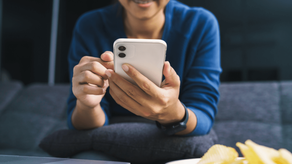 a person holding a cell phone while sitting at a table