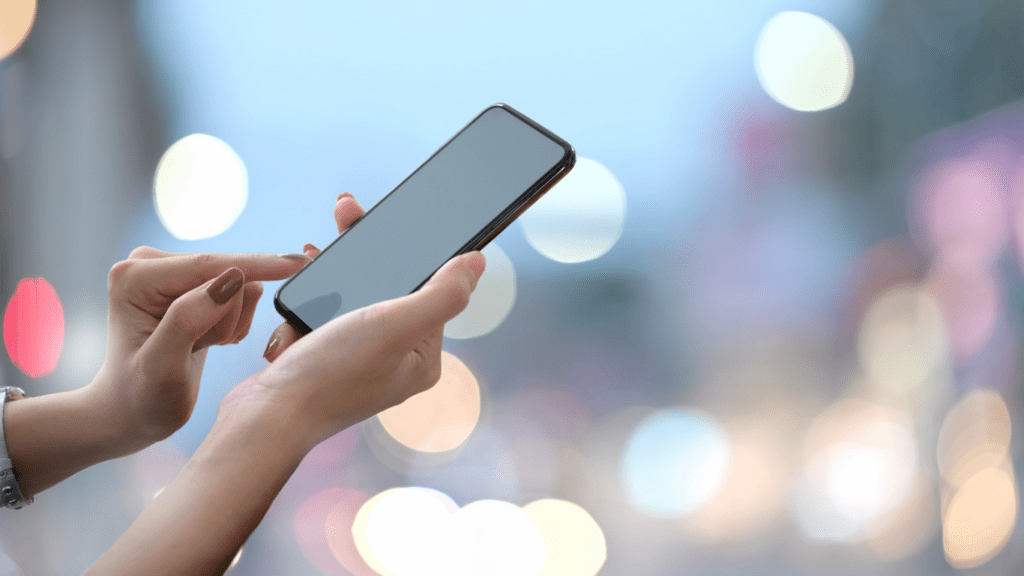 a person holding up a smart phone in front of a blurred background