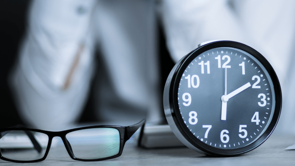 a clock and glasses sitting on a desk