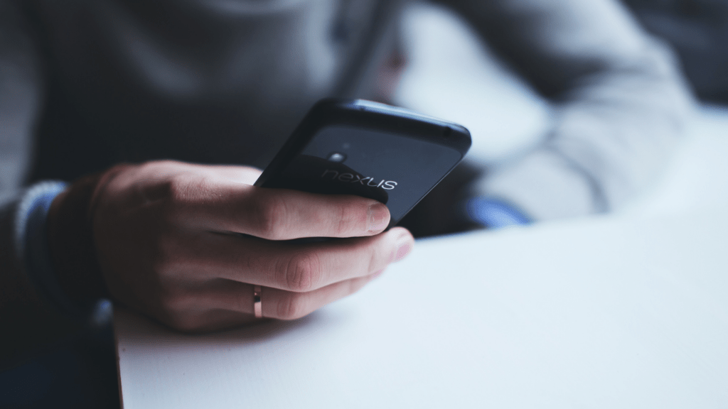 a person holding a cell phone while sitting at a table