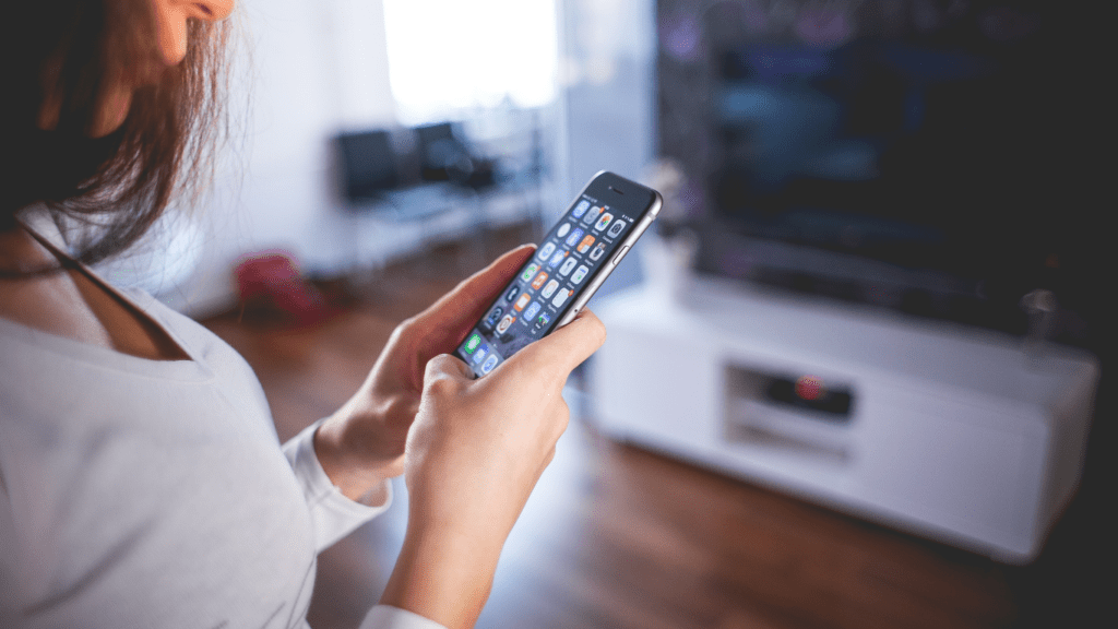 a person holding up a smart phone in front of a blurred background