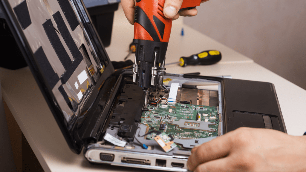 a person is repairing a laptop with a screwdriver